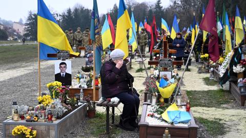 An elderly woman grieves next to the grave of a Ukrainian soldier during Ukraine's Army Day in Lviv, Ukraine, on December 6, 2022. (Yuriy Dyachyshyn/AFP via Getty Images)