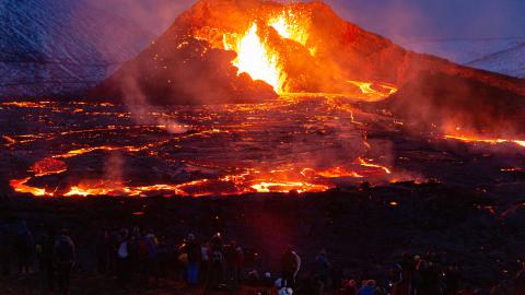 People's figures are illuminated by the glow of the lava on March 28, 2021 on the Reykjanes Peninsula, Iceland. The Mount Fagradalsfjall volcano erupted on March 19, after thousands of small earthquakes in the area over the recent weeks, and was reportedly the first eruption of its kind on the Reykjanes Peninsula in around 800 years. (Photo by Sophia Groves/Getty Images)