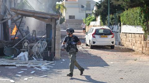  A member of the Israeli forces runs past a fire raging in a house in Ashkelon following a rocket attack from the Gaza Strip on southern Israel on October 7, 2023. Palestinian militant group Hamas has launched a "war" against Israel, Defence Minister Yoav Gallant said, after barrages of rockets were fired from the Gaza Strip into Israeli territory on October 7. (Photo by AHMAD GHARABLI / AFP) (Photo by AHMAD GHARABLI/AFP via Getty Images)