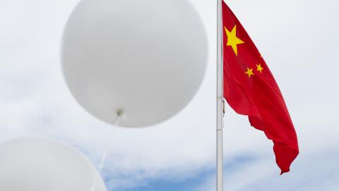 Two white balloons float near the Chinese flag during a demonstration outside the Chinese Embassy in Washington, DC, on February 15, 2023. (Photo by Saul Loeb/AFP via Getty Images)