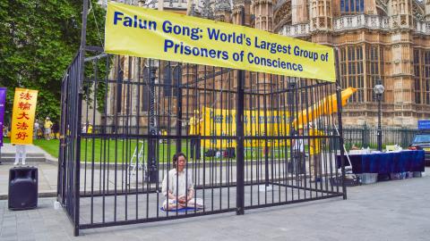 A Falun Gong demonstrator sits in a cage in London, United Kingdom, on July 18, 2021, during the protest against the Chinese government's persecution. (Vuk Valcic/SOPA Images/LightRocket via Getty Images)