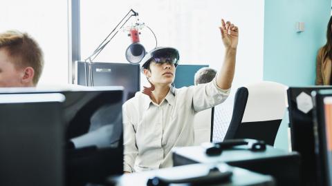 Female engineer testing program on augmented reality headset in computer lab 